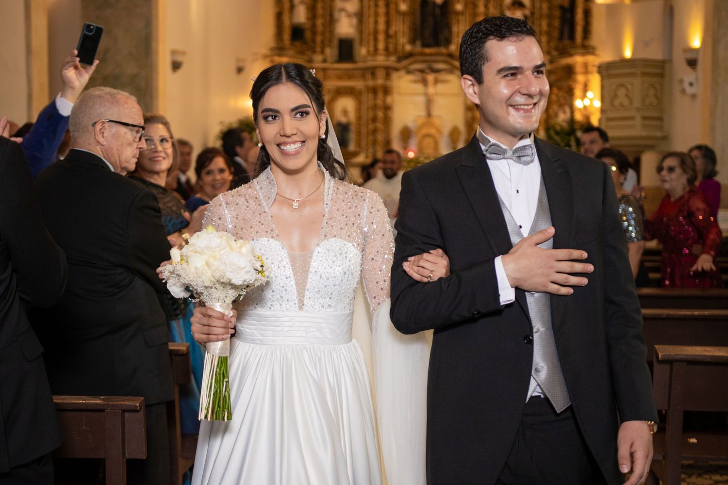 Jubilant newlyweds exit their wedding ceremony while guests cheer and take photos. Boda en Parras Coahuila, Fotógrafo de bodas