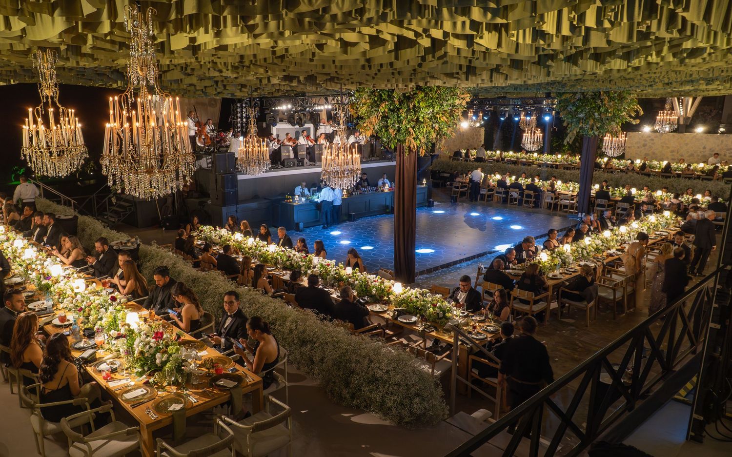 Elegant wedding reception venue with long tables, crystal chandeliers, and warm ambient lighting creating a romantic atmosphere.
