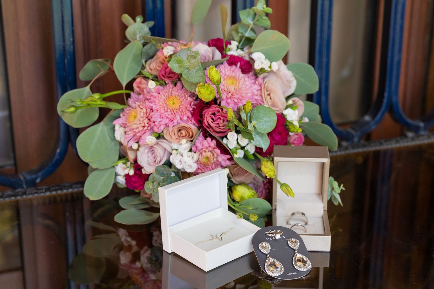 Pink and burgundy wedding bouquet with greenery displayed next to jewelry boxes. Boda en Parras Coahuila, Fotógrafo de bodas