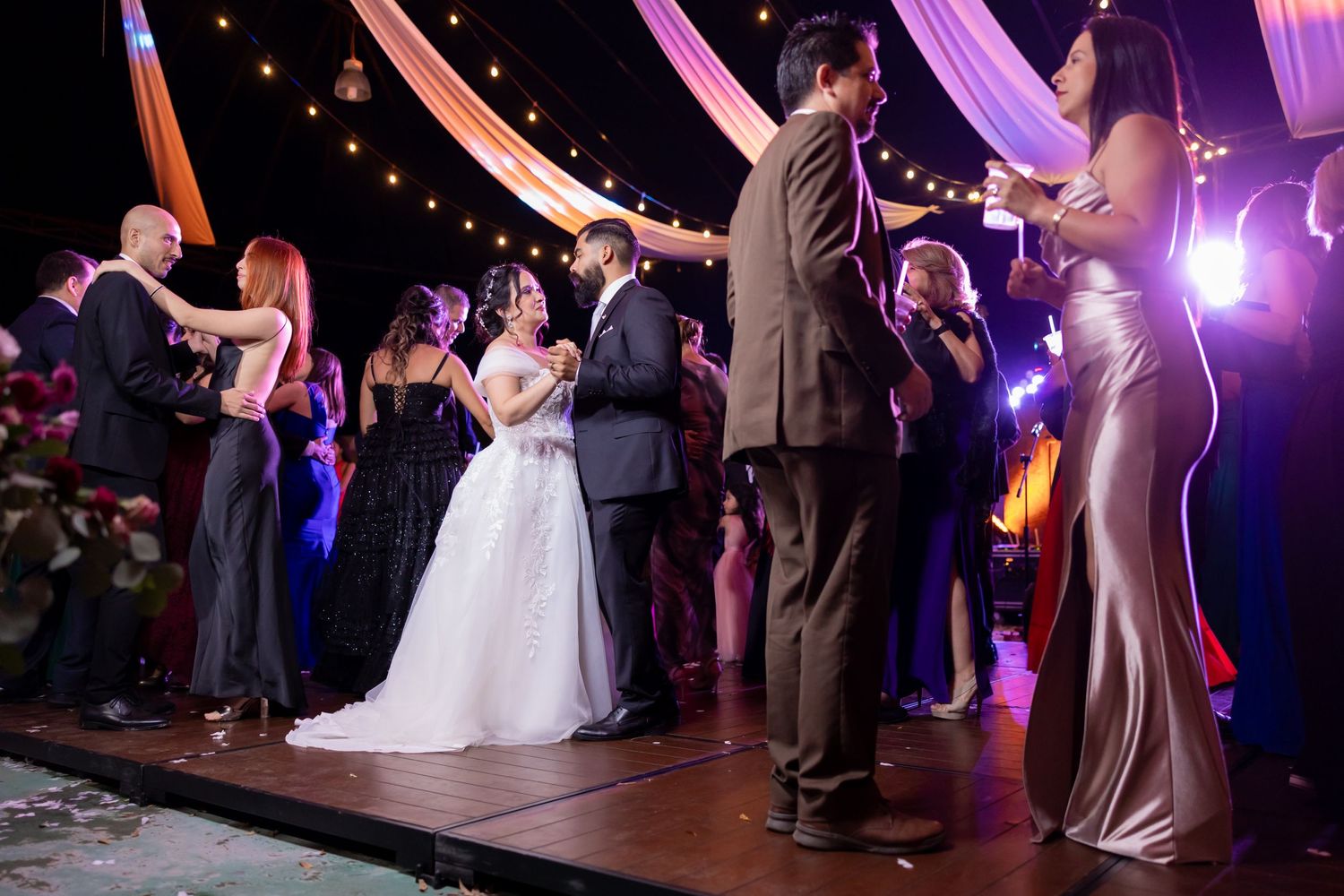 Wedding couples and guests slow dance under elegant fabric draping and string lights. Boda en Parras Coahuila, Fotógrafo de bodas