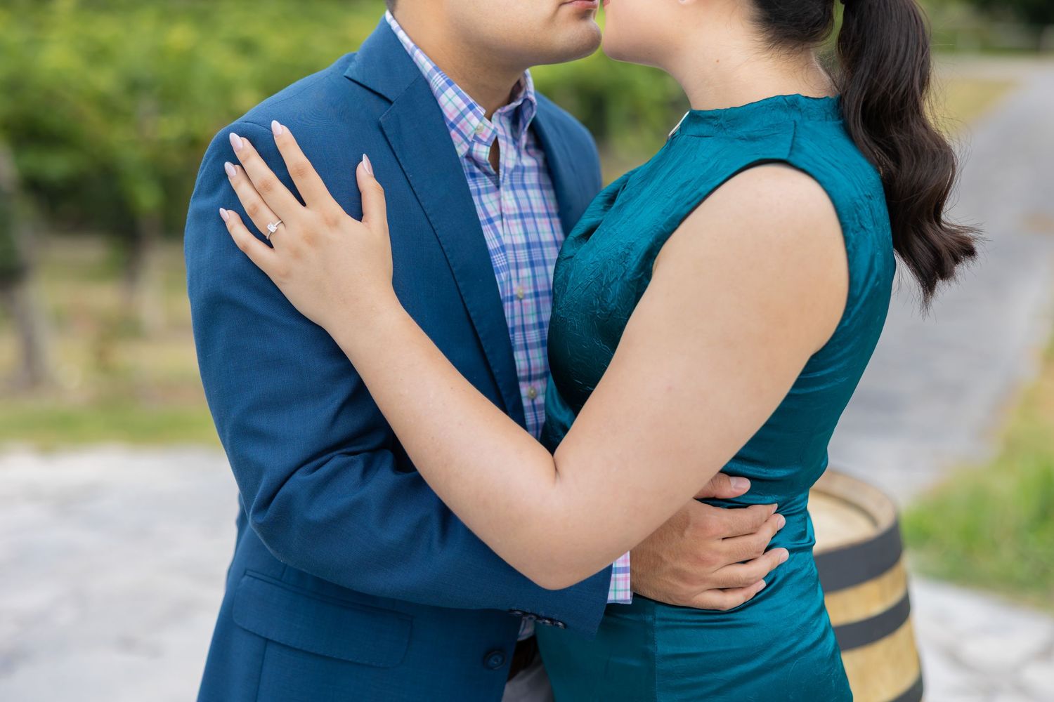A couple in teal and plaid embraces during an outdoor photo session in a garden setting.