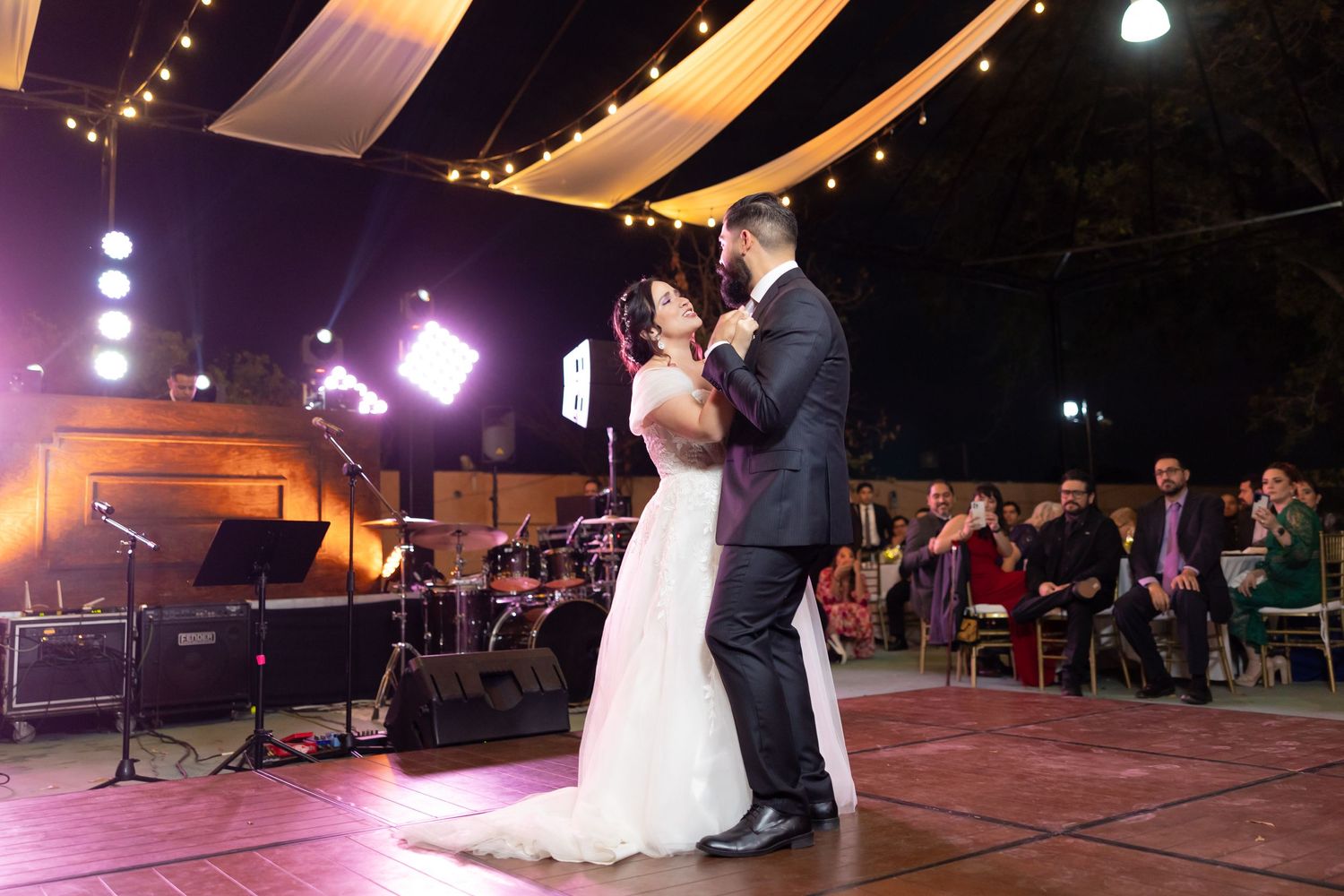 Wedding couple dances under draped fabric and string lights at their reception. Boda en Parras Coahuila, Fotógrafo de bodas