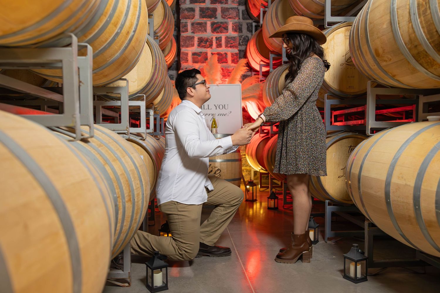 A romantic marriage proposal scene between two people in a wine cellar surrounded by wooden barrels.