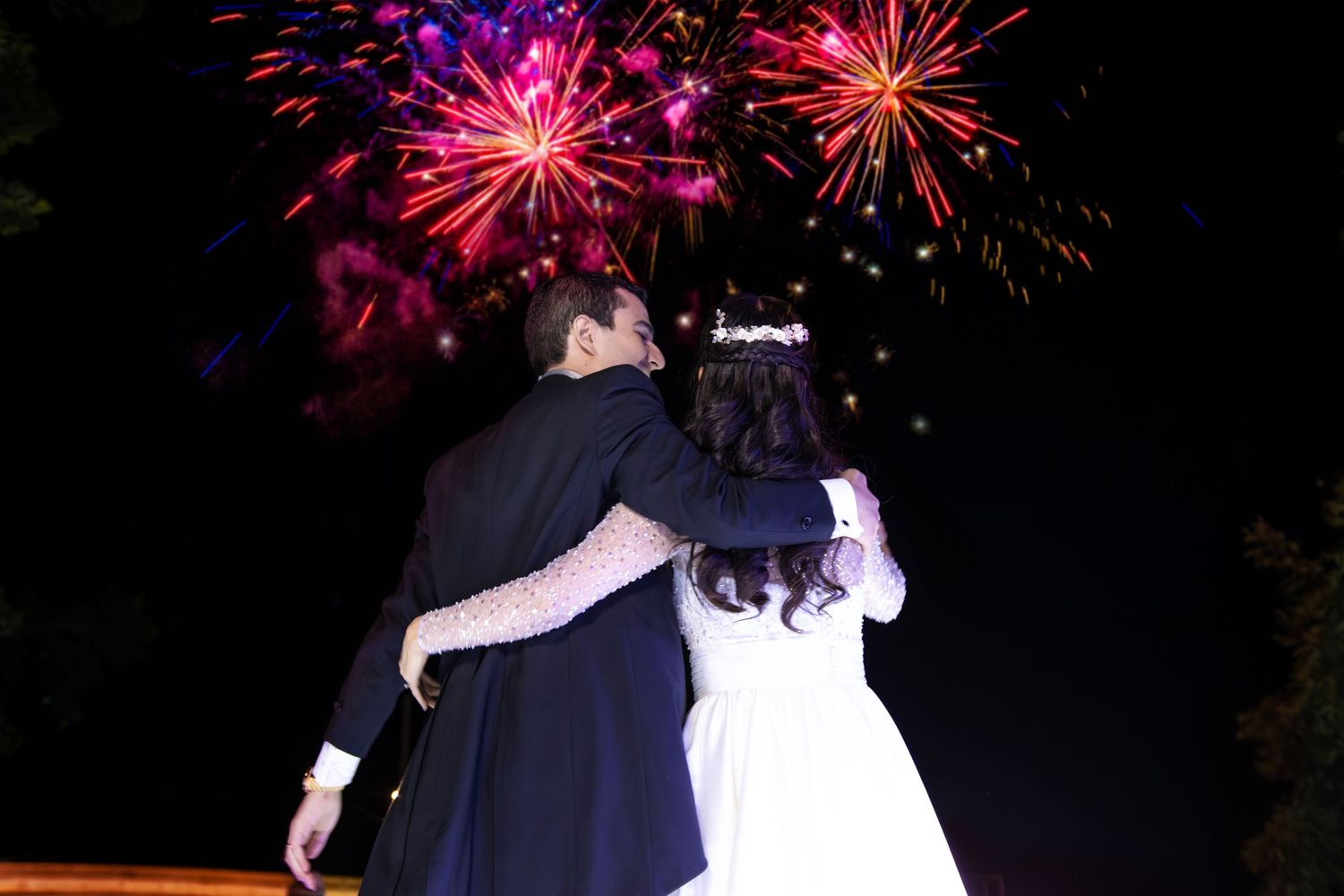 A wedding couple watches fireworks display together during their nighttime celebration. Boda en Parras Coahuila, Fotógrafo de bodas