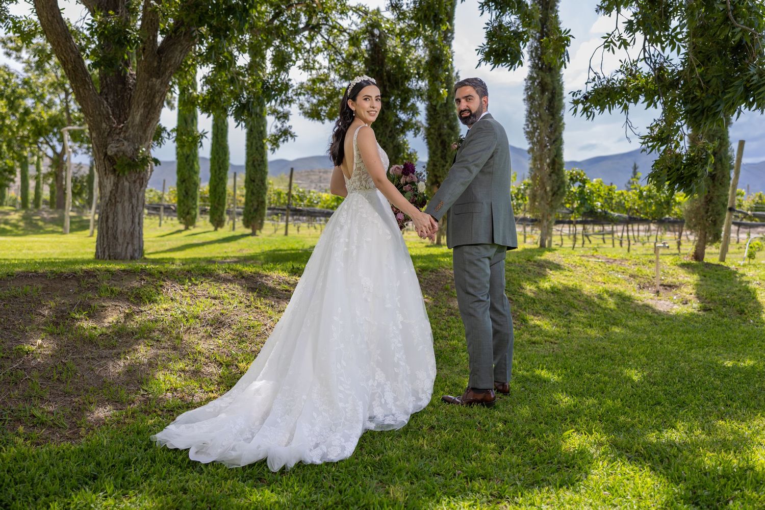 A stunning wedding portrait in a tree-lined venue with mountains visible in the distance. Boda en Parras Coahuila fotógrafo