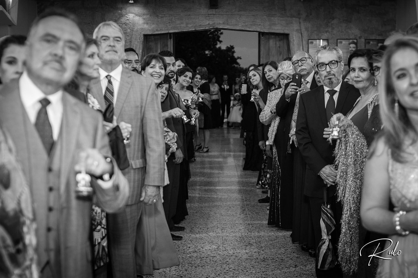 Black and white photo of wedding guests watching ceremony procession from church pews. boda en Parras Coahuila fotógrafo