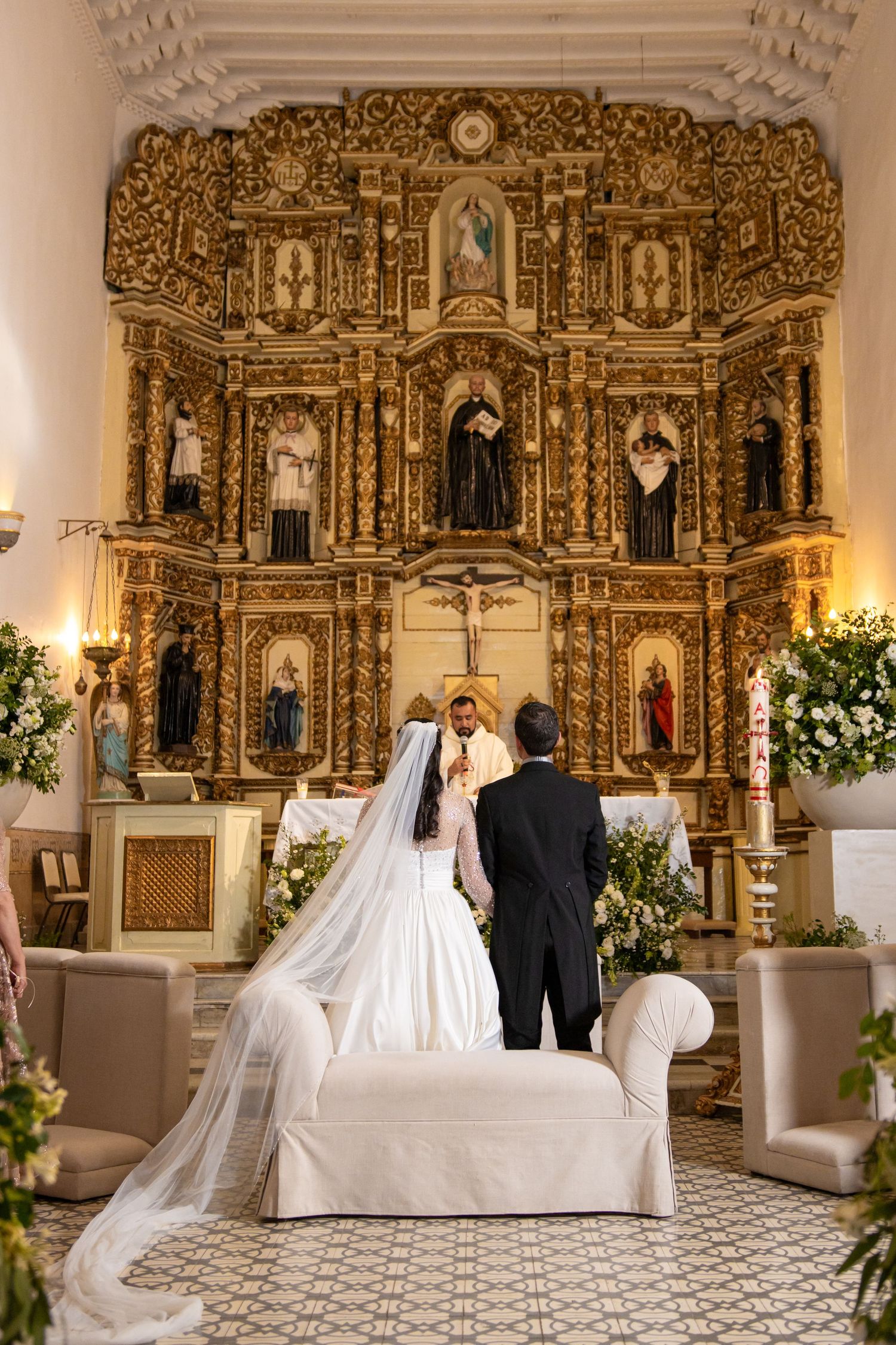 Couple stands before an elaborately carved golden altar during their wedding ceremony. Boda en Parras Coahuila, Fotógrafo de bodas