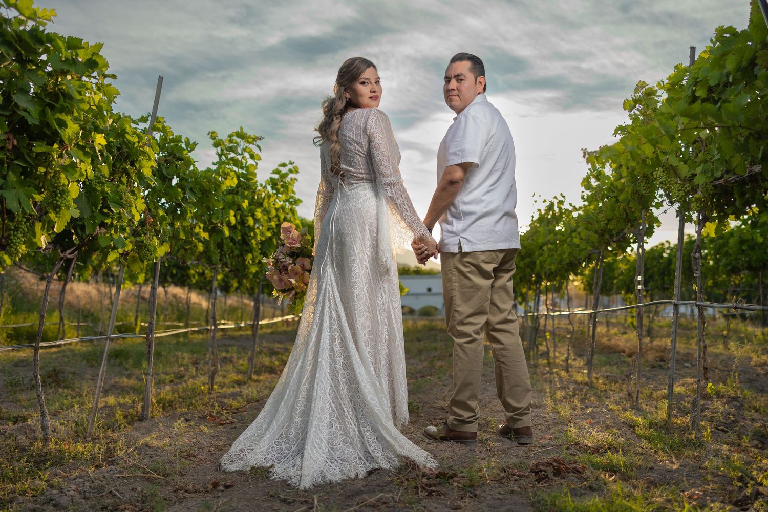 A couple poses together in a vineyard wearing formal attire. Sesión en Parras Coahuila