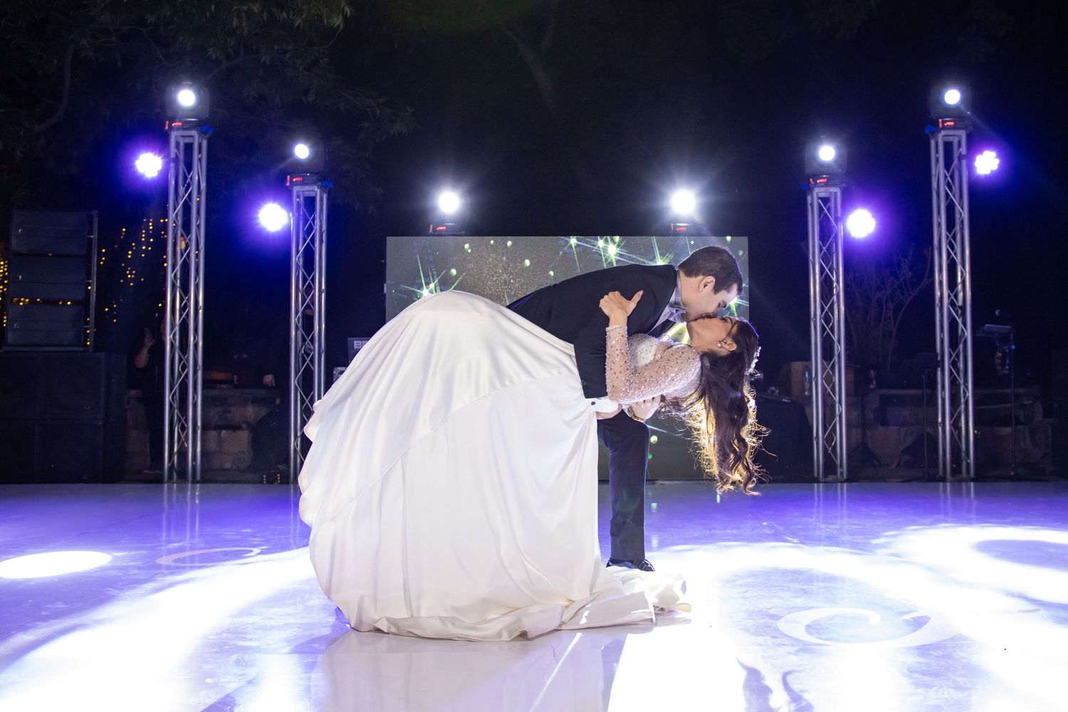 A dramatic wedding dance dip performed on a circular illuminated stage with purple accent lighting. Boda en Parras Coahuila, Fotógrafo