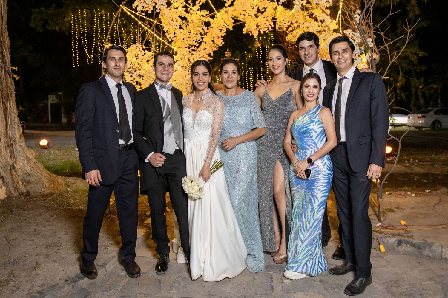 Wedding party group photo at night with elegant formal attire under string lights. Boda en Parras Coahuila, Fotógrafo de bodas