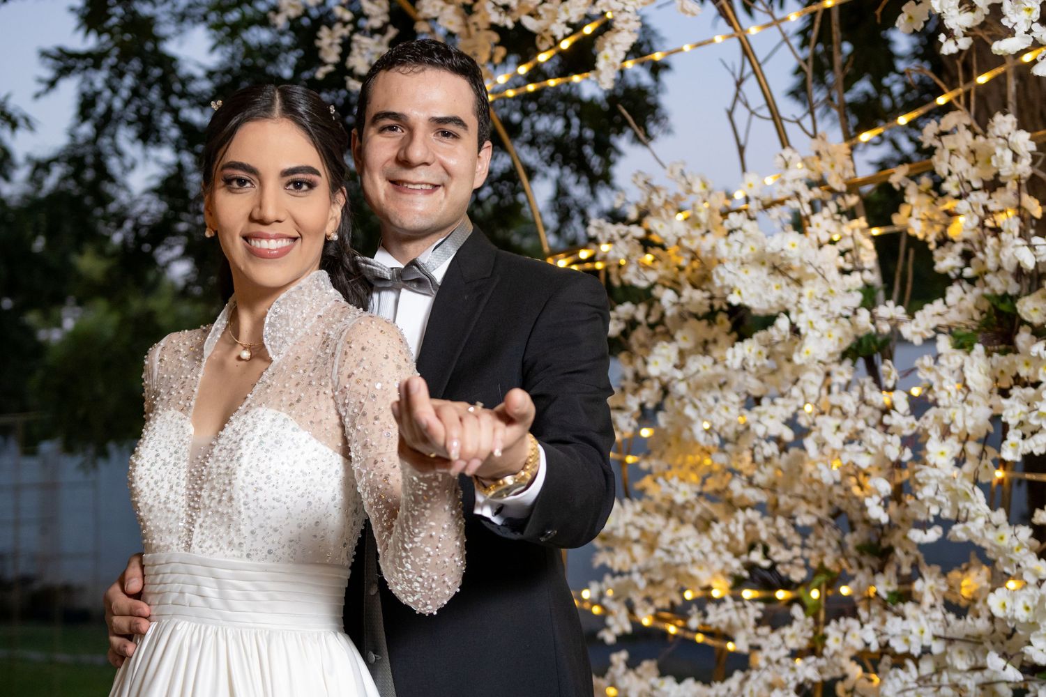 Wedding couple poses with confetti against illuminated cherry blossom backdrop. Boda en Parras Coahuila, Fotógrafo de bodas