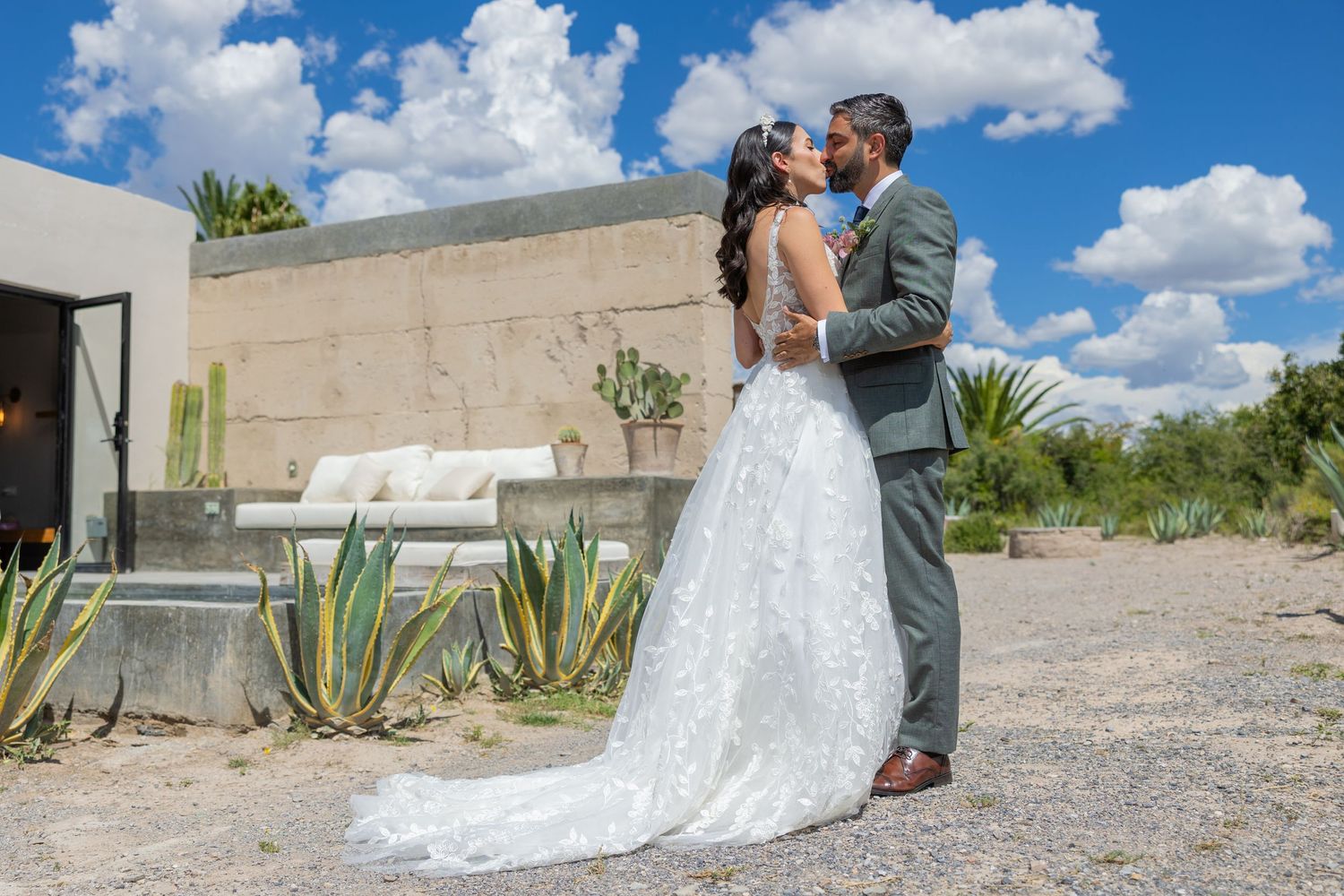 A romantic wedding moment captured in front of a modern building with desert landscaping. Boda en Parras Coahuila fotógrafo