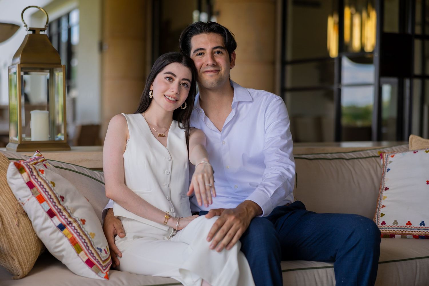 A couple in white and blue outfits relaxing on a couch with decorative pillows. Propuesta de matrimonio Parras, Fotografo