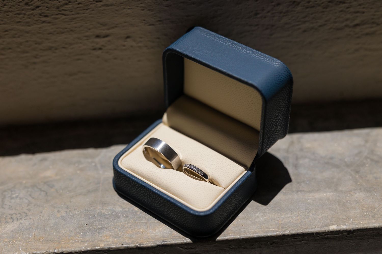 Wedding rings displayed in a navy blue jewelry box in sunlight. Boda en Parras Coahuila fotógrafo