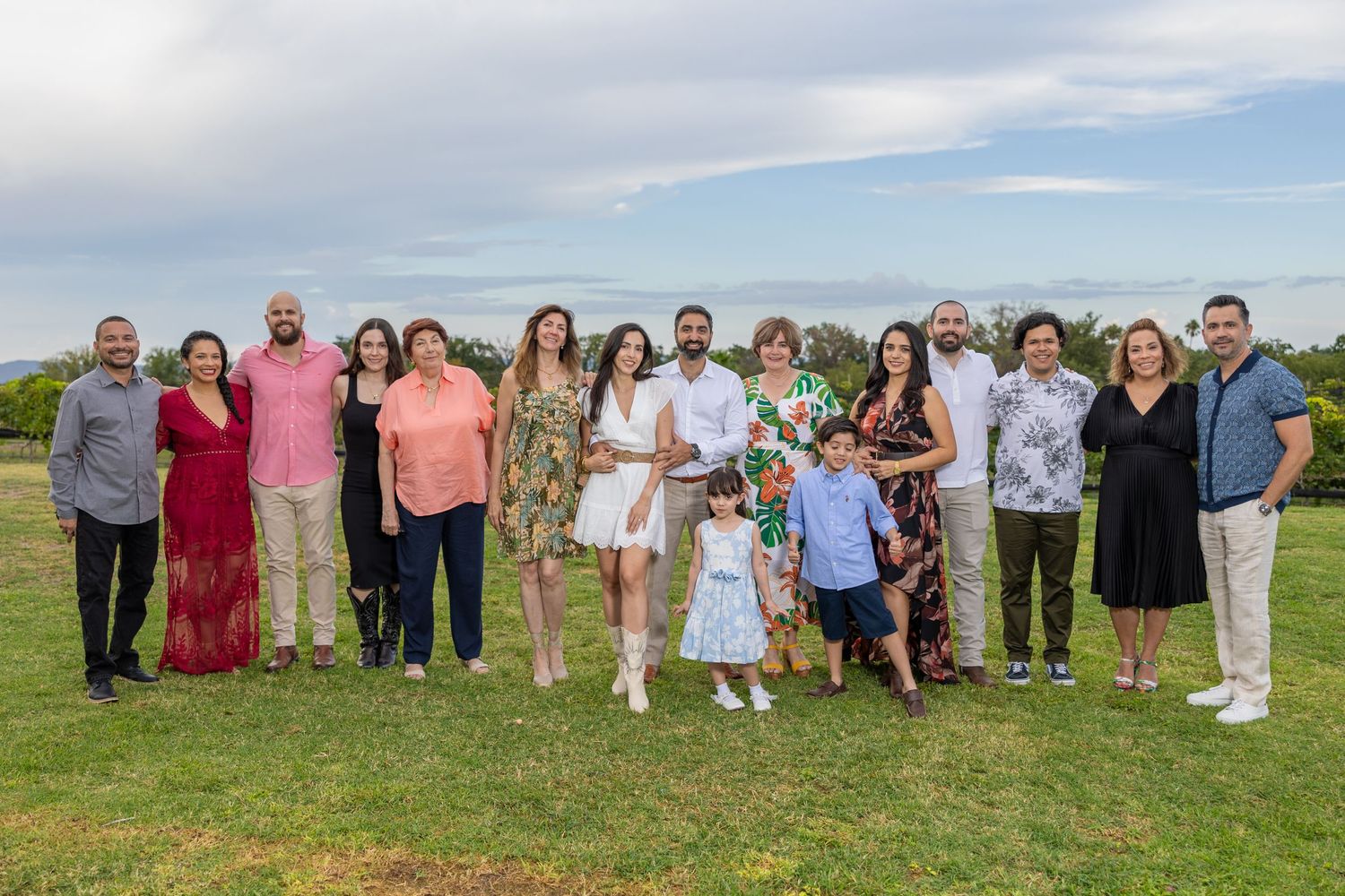 Large group gathered on a grassy hillside for an outdoor celebration on a sunny day. Boda en Parras Coahuila fotógrafo