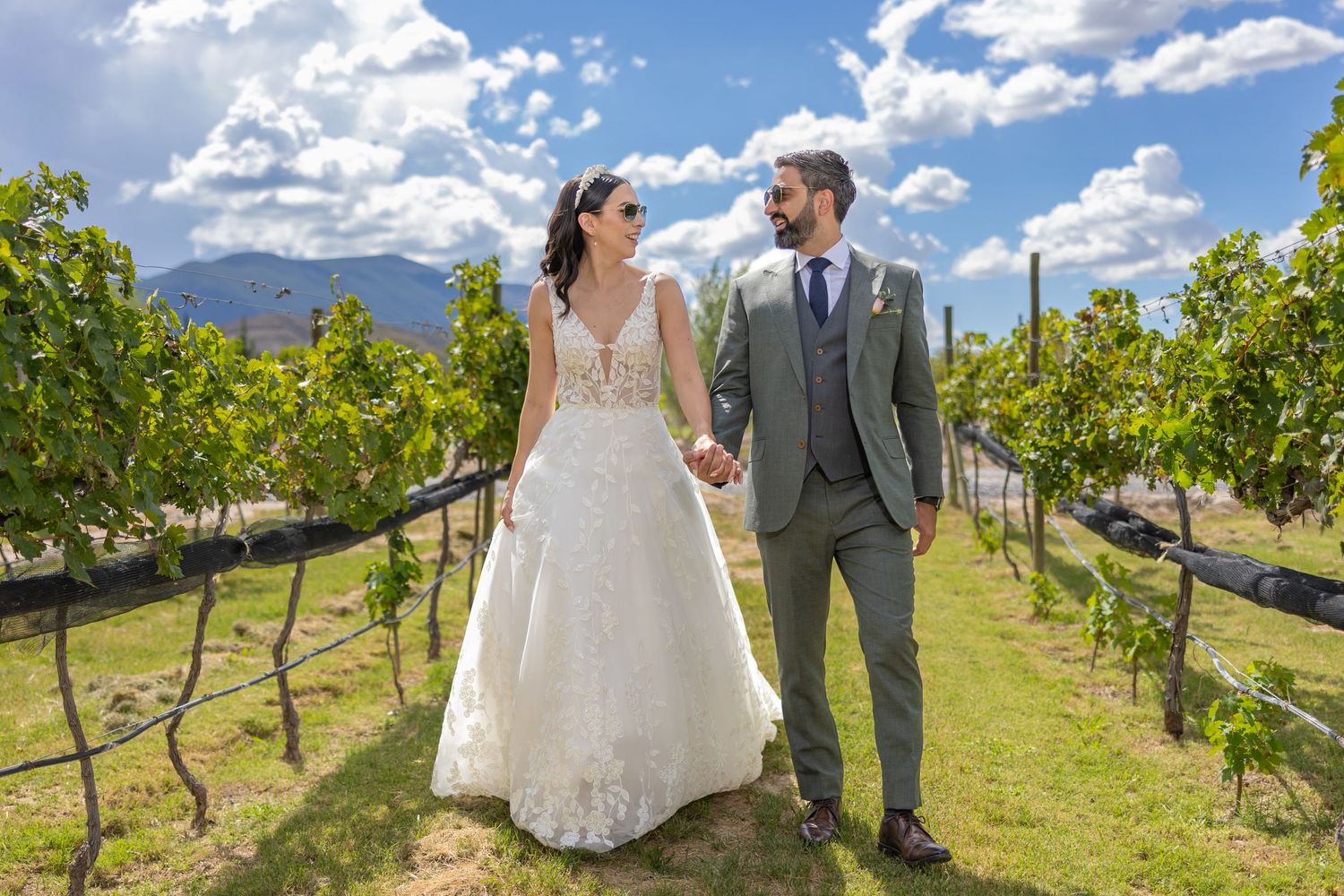 Newlyweds walking together through scenic vineyard rows on sunny day. Boda en Parras Coahuila fotógrafo