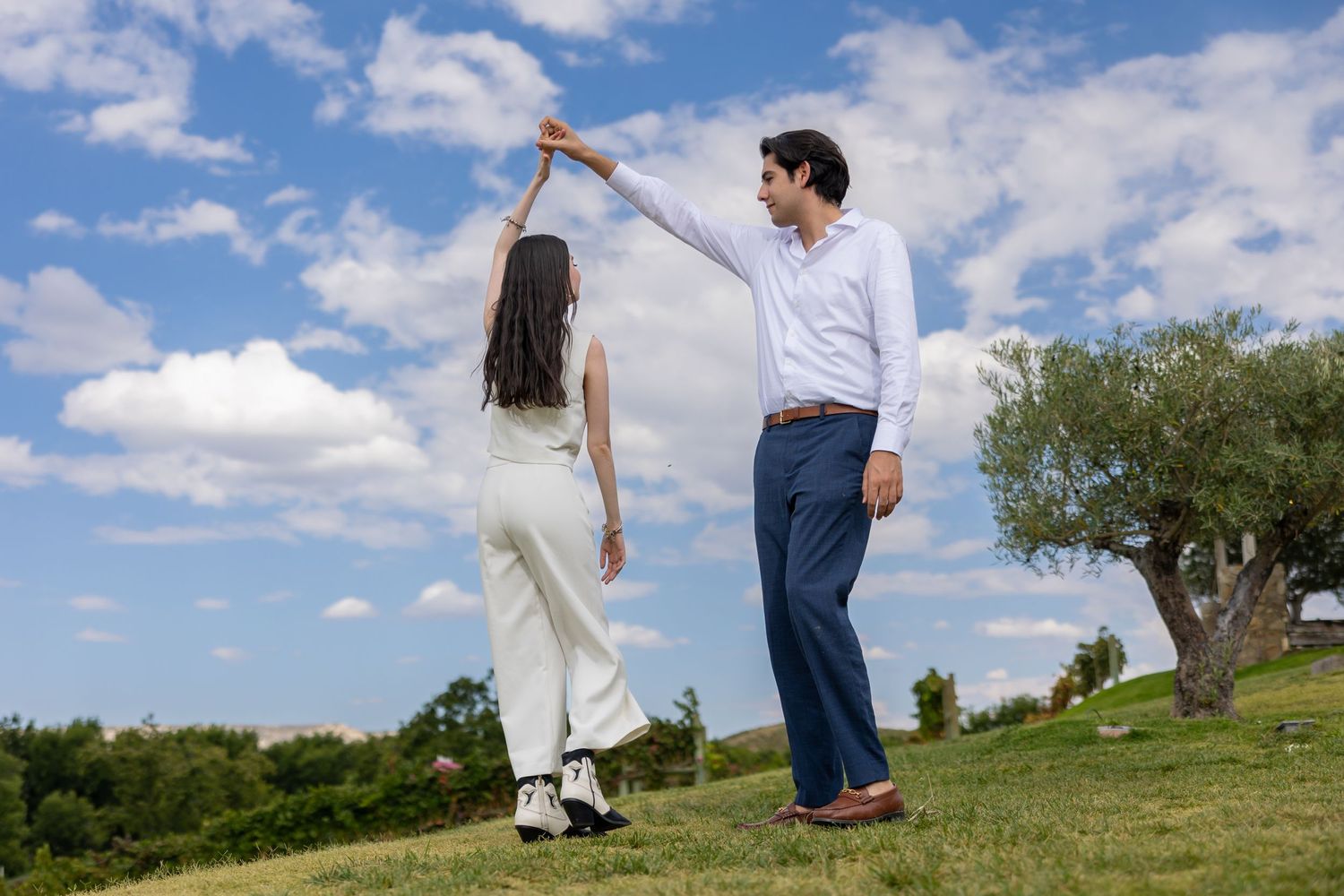 A couple dances together on a grassy hill against a bright blue sky. Propuesta de matrimonio Parras, Fotografo