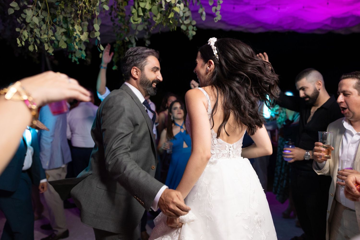 Couple sharing an energetic dance moment at their wedding reception under purple mood lighting. Boda en Parras Coahuila fotógrafo