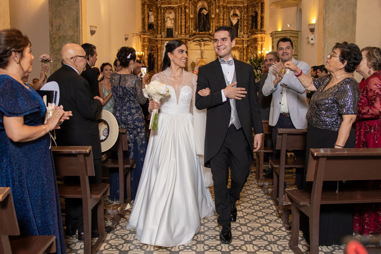 Newlyweds walk down the church aisle while guests celebrate their marriage. Boda en Parras Coahuila, Fotógrafo de bodas