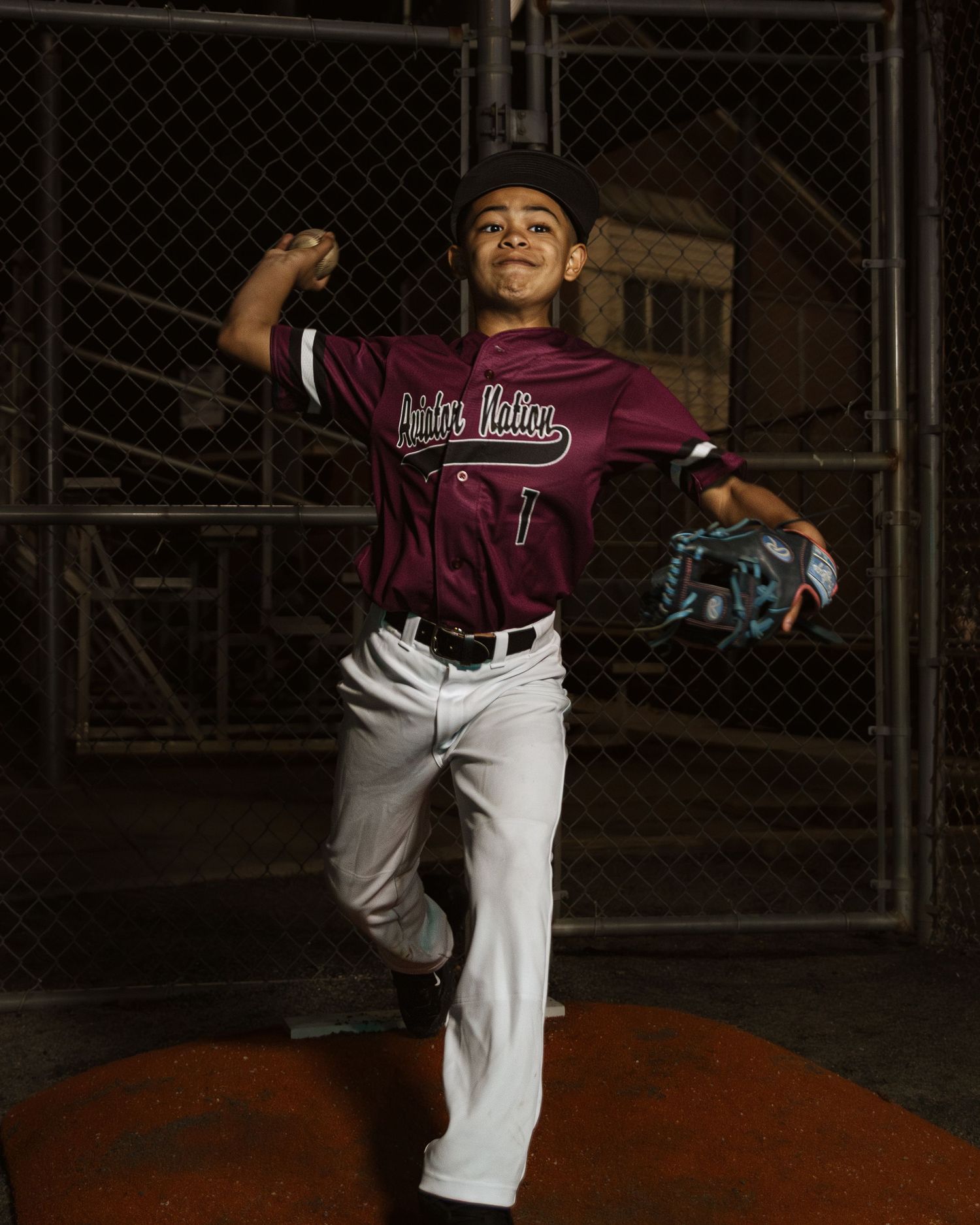Youth baseball player in maroon uniform demonstrating pitching form on field.