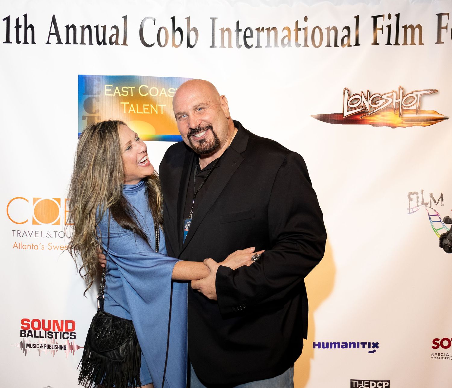 People pose together on a red carpet at a film festival with event signage and banners visible in the background.