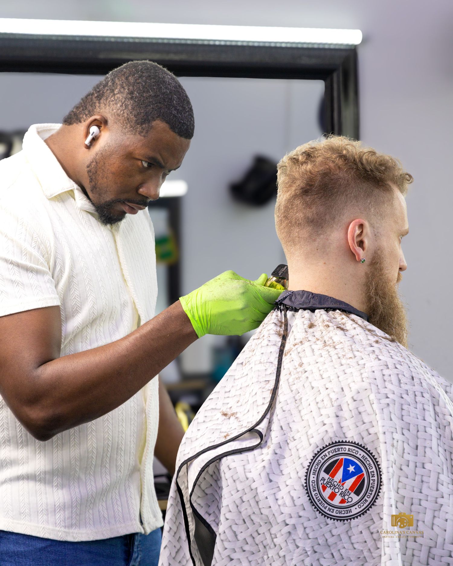 A barber carefully trims a client's hair with professional clippers in a modern barbershop setting.