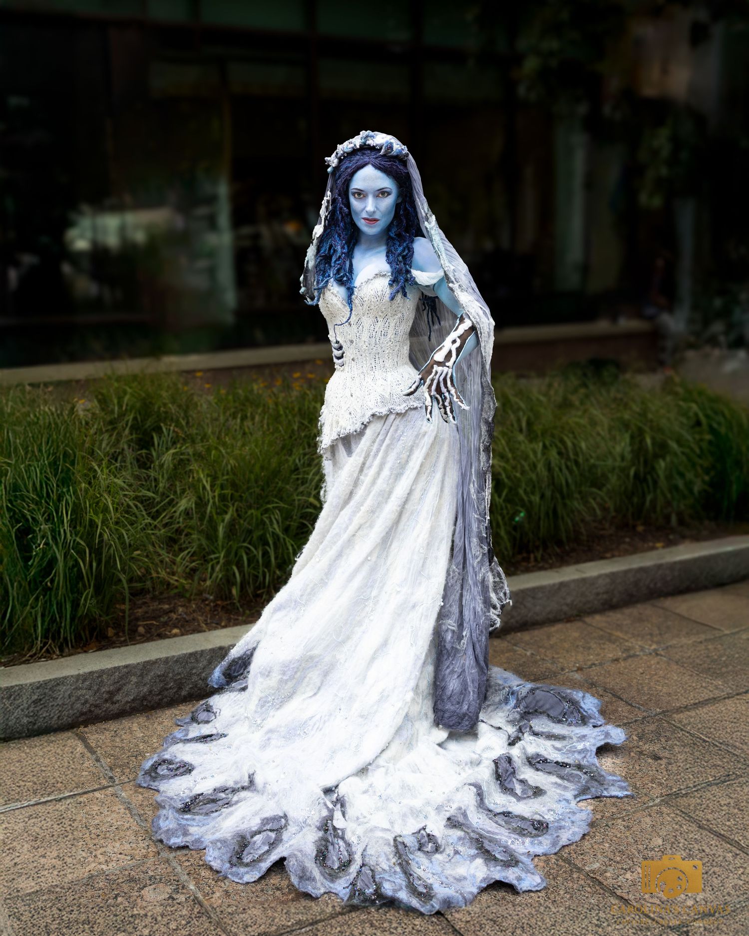 Person dressed as the Corpse Bride in blue body paint, tattered white wedding gown, and veil costume.