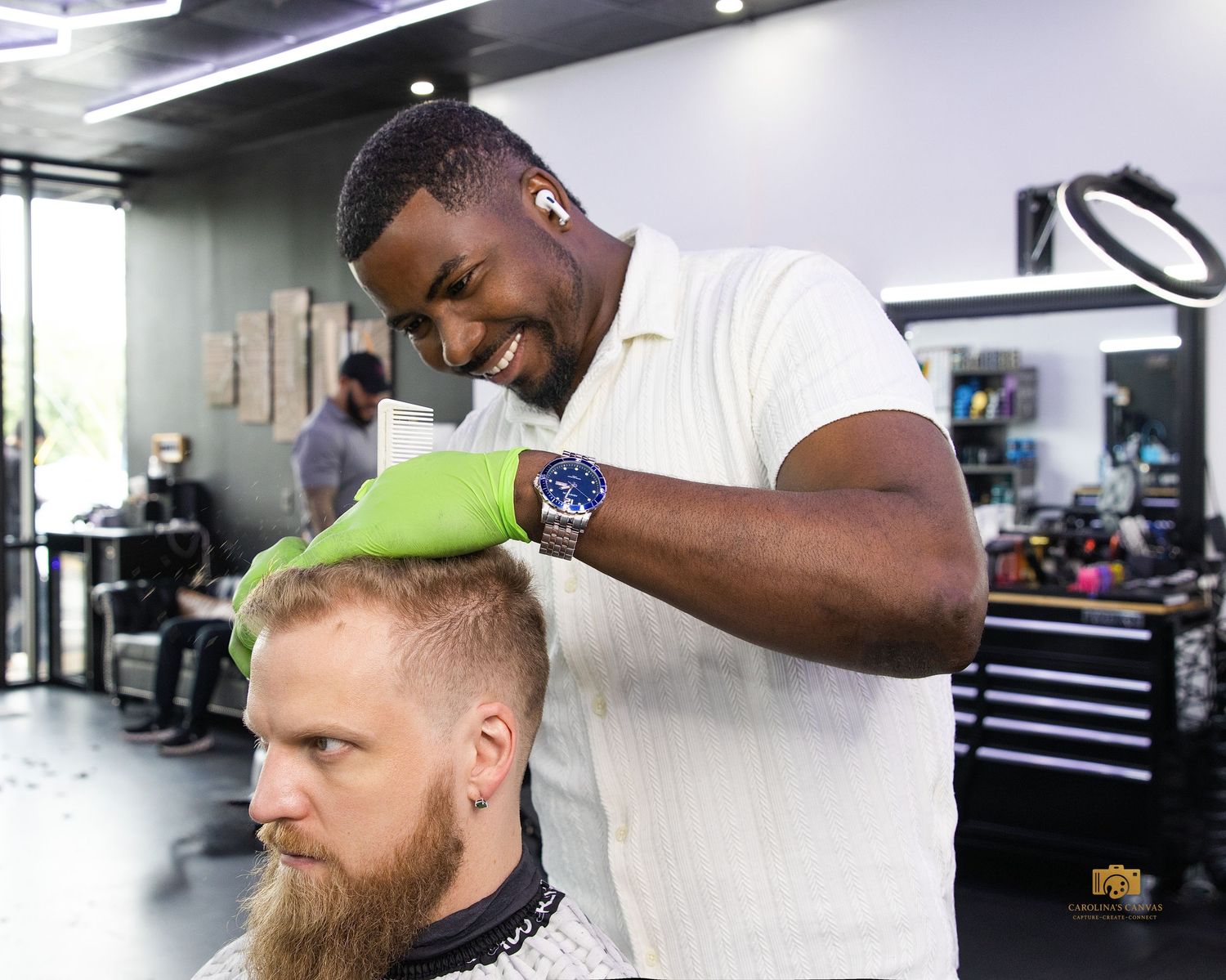 Professional barber carefully trimming and styling a client's beard at a modern barbershop.
