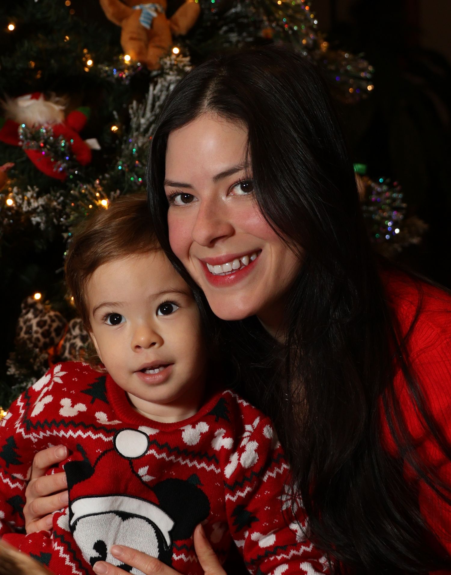 A festive Christmas scene with red holiday sweaters and twinkling lights in the background.
