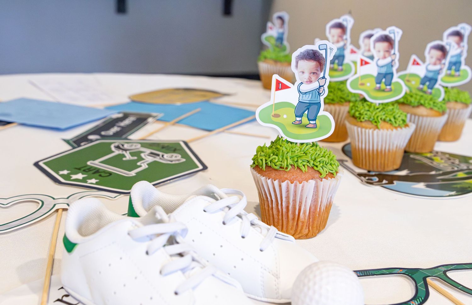 Decorative paper cutouts and cupcakes arranged on a white surface for a party celebration.