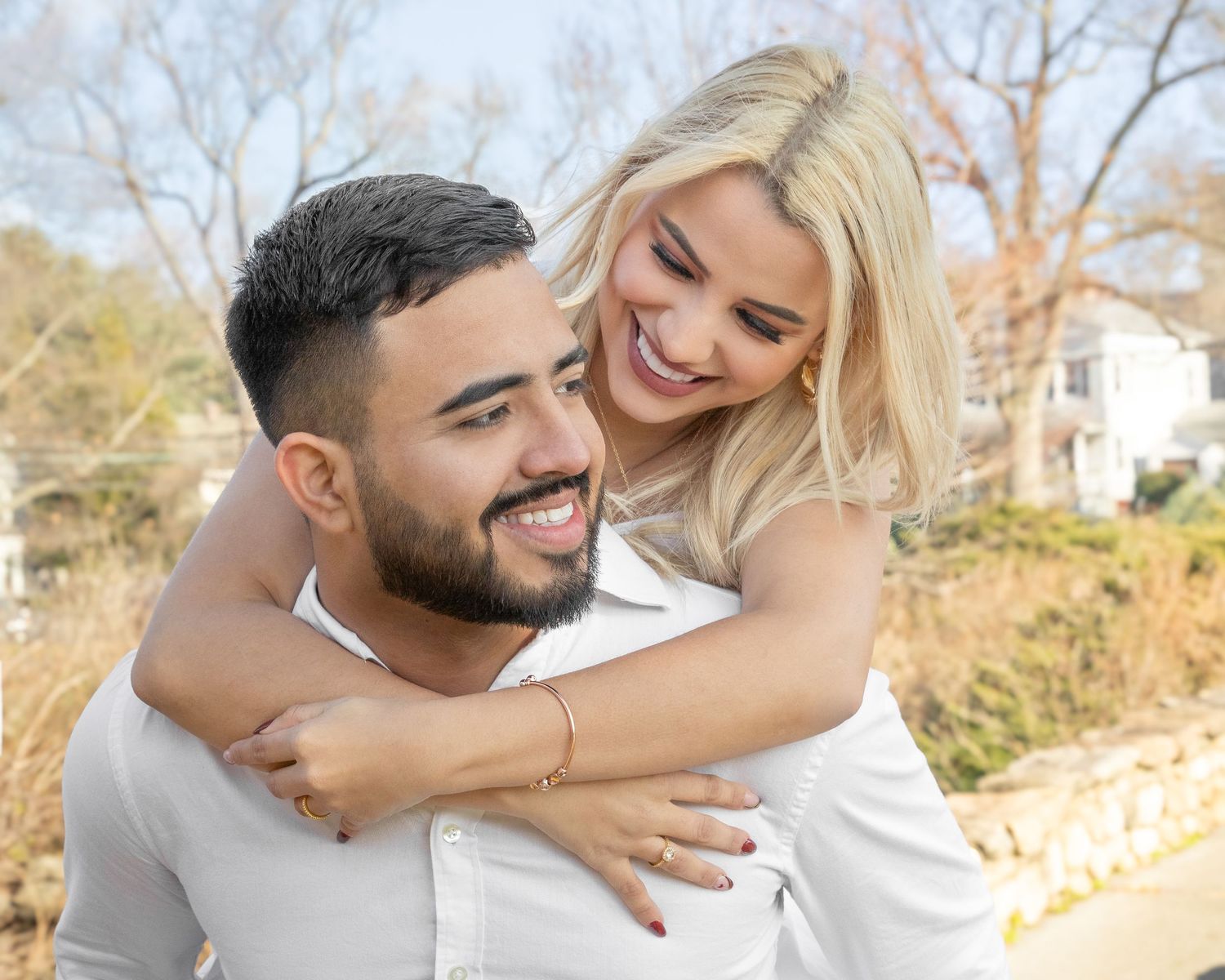 A happy couple embraces outdoors during a sunny autumn day, sharing a joyful moment together.