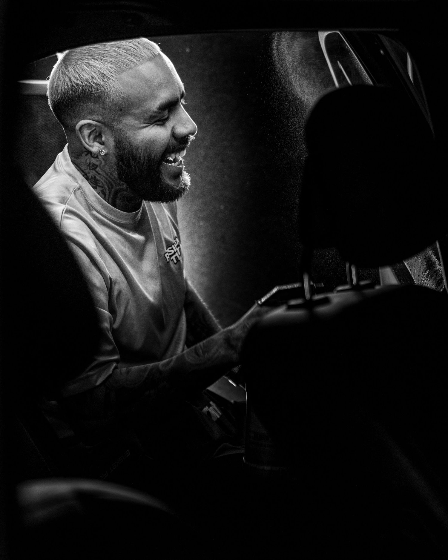 Black and white portrait of a musician smiling while seated at a piano in a dark performance setting.
