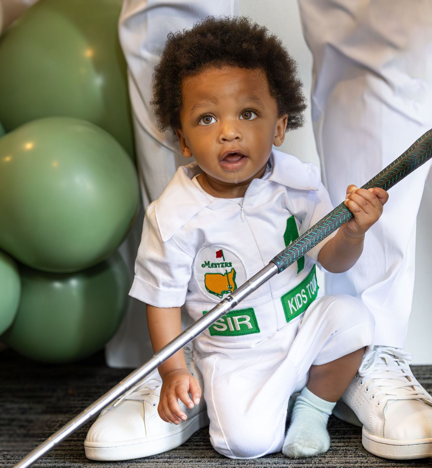 Child in white t-shirt with green balloon sits on wooden floor showing playful expressions in progression.