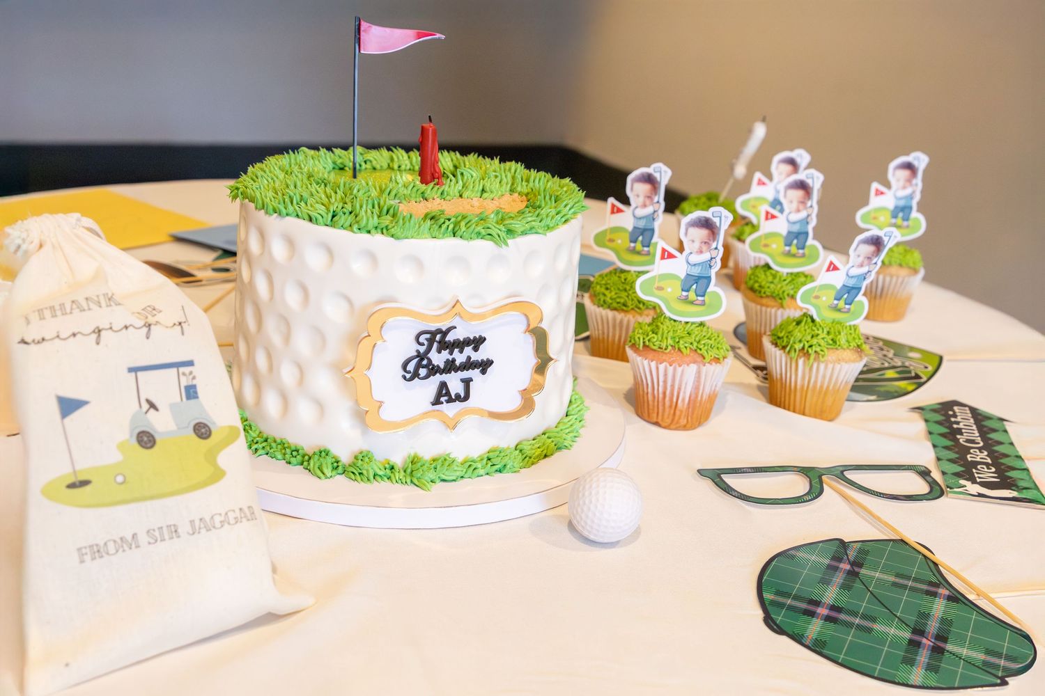 A long table decorated for a celebration with green and white themed cakes, cupcakes, and party decorations.