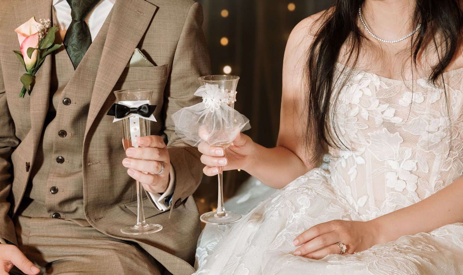 Bride and groom toasting with decorated champagne glasses at wedding reception.
