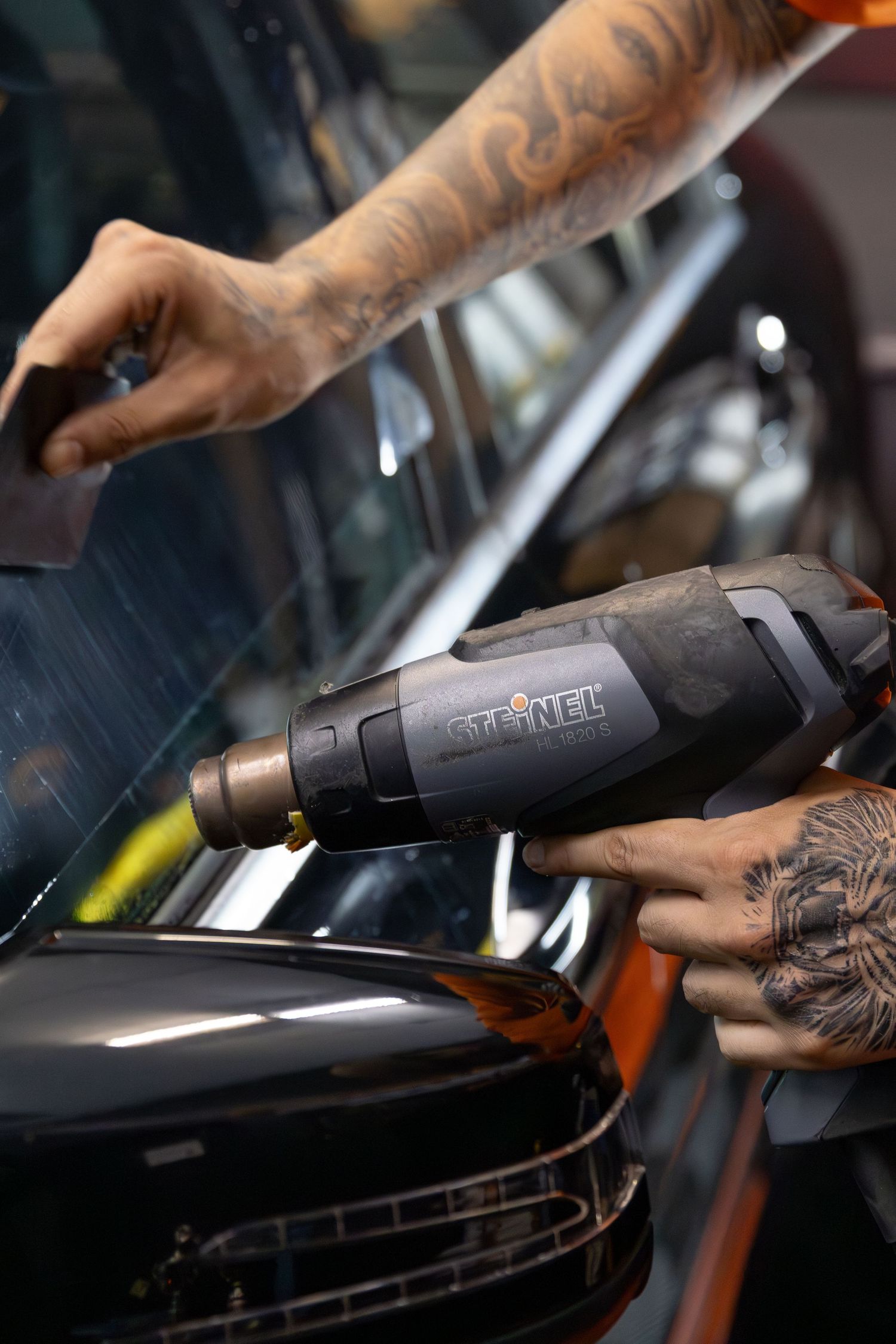 Tattooed hands using a Gtech cleaning tool to detail and vacuum the interior of a dark vehicle. marketing and business photography