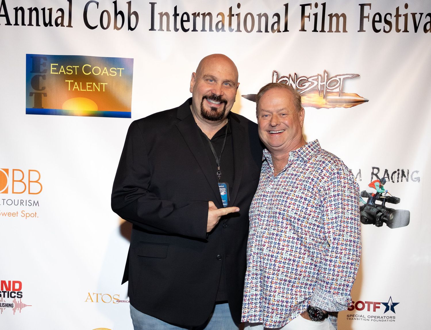 Event attendees pose together at the 11th Annual Cobb International Film Festival against a backdrop with sponsor logos.