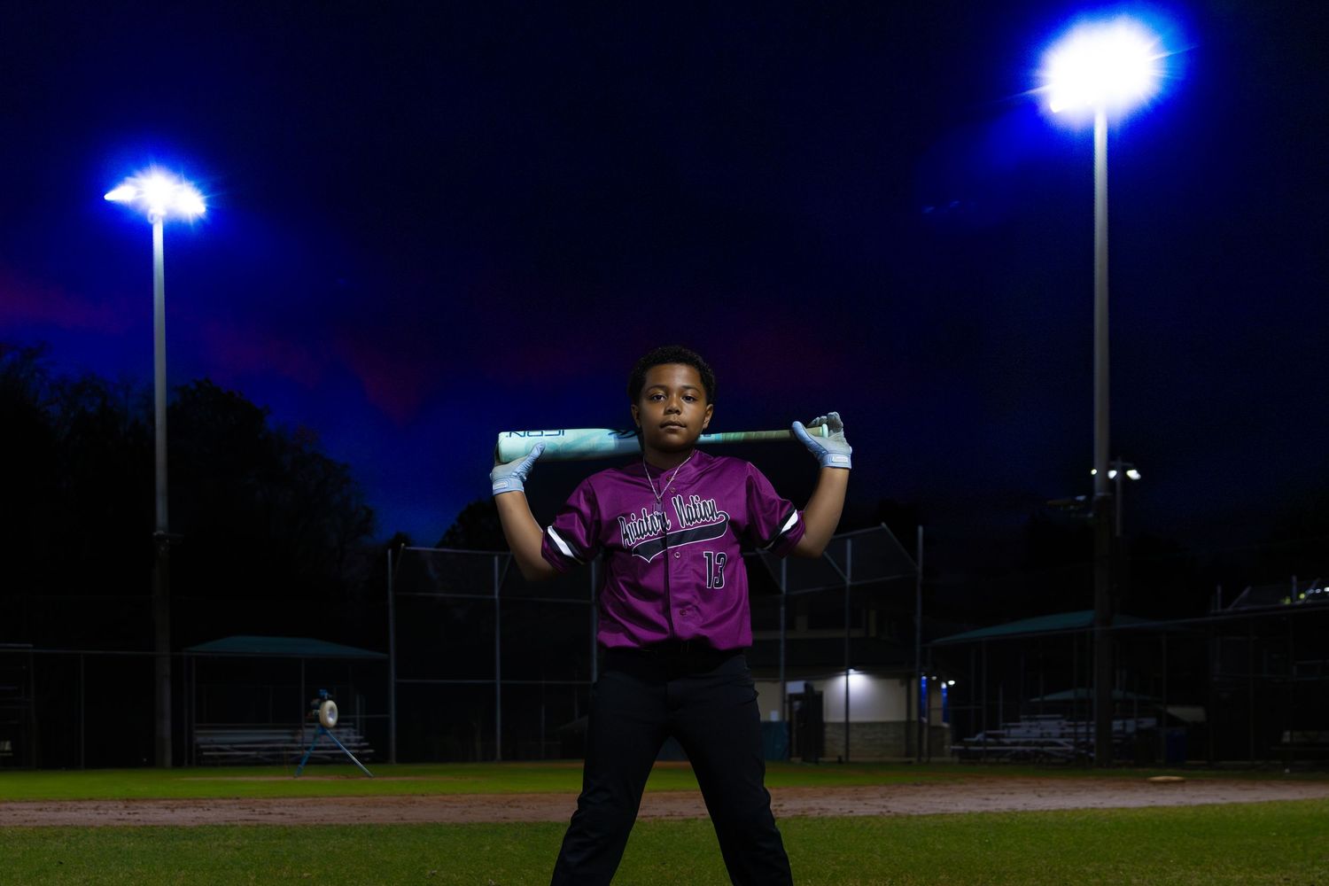 Blue stadium lights illuminate an empty sports field at night.