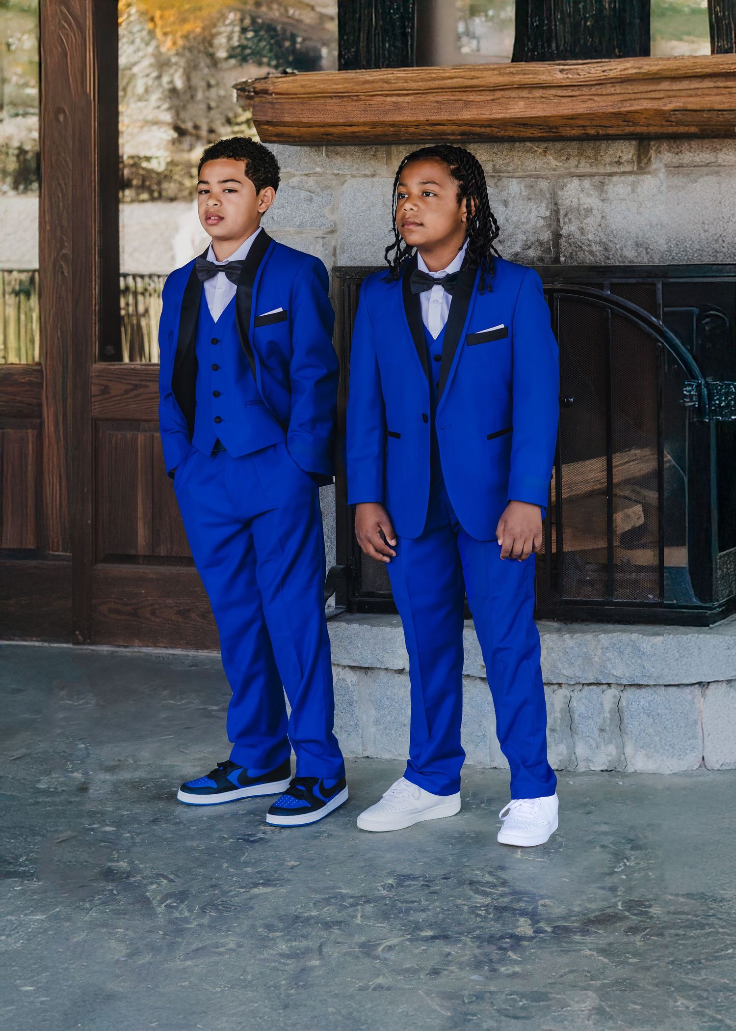 Two people pose in matching bright blue formal suits with bow ties and sneakers.