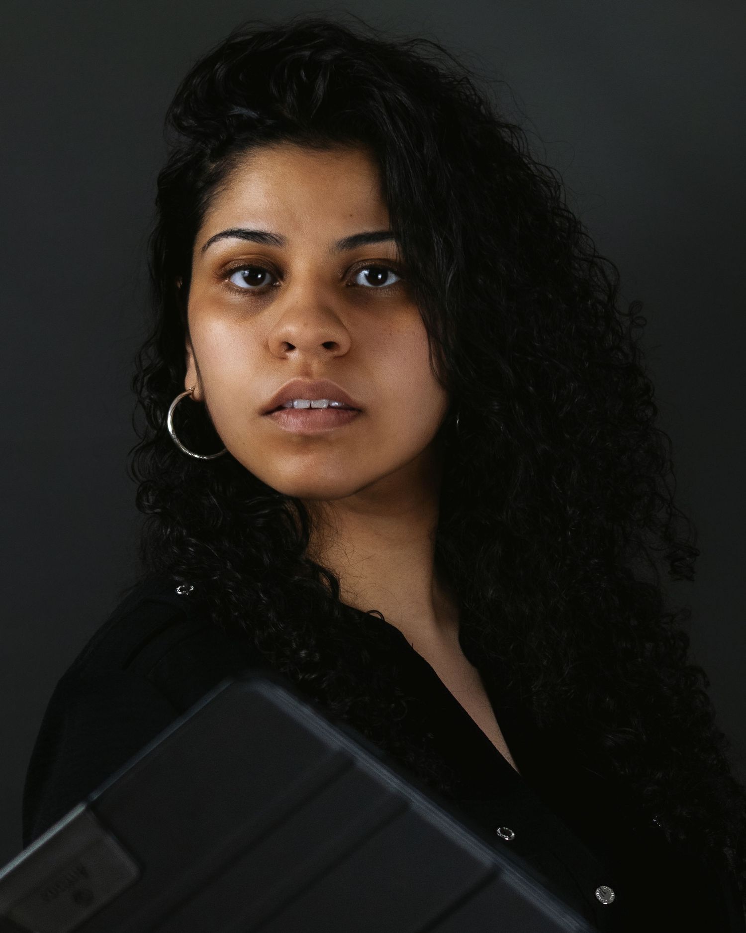 A stylized portrait series with dark backdrop showcasing a person with curly hair wearing a black top.