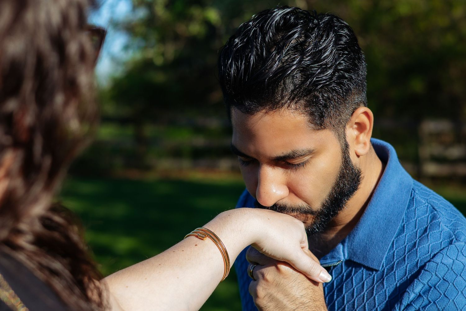 Person in blue shirt sitting outdoors with head down in a series of progressive poses against natural background.