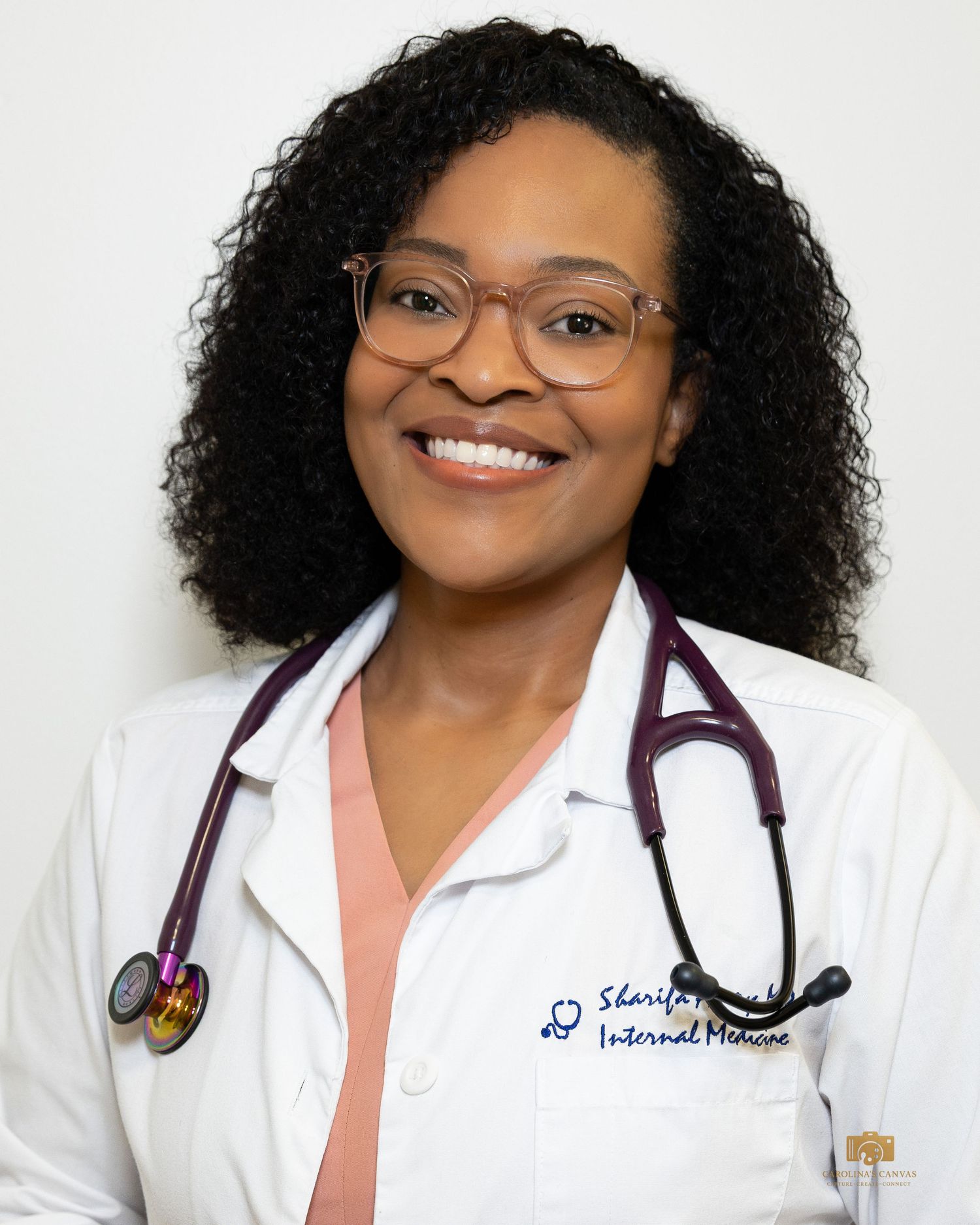 Smiling female doctor in white coat with stethoscope and glasses, Internal Medicine specialist professional headshot.