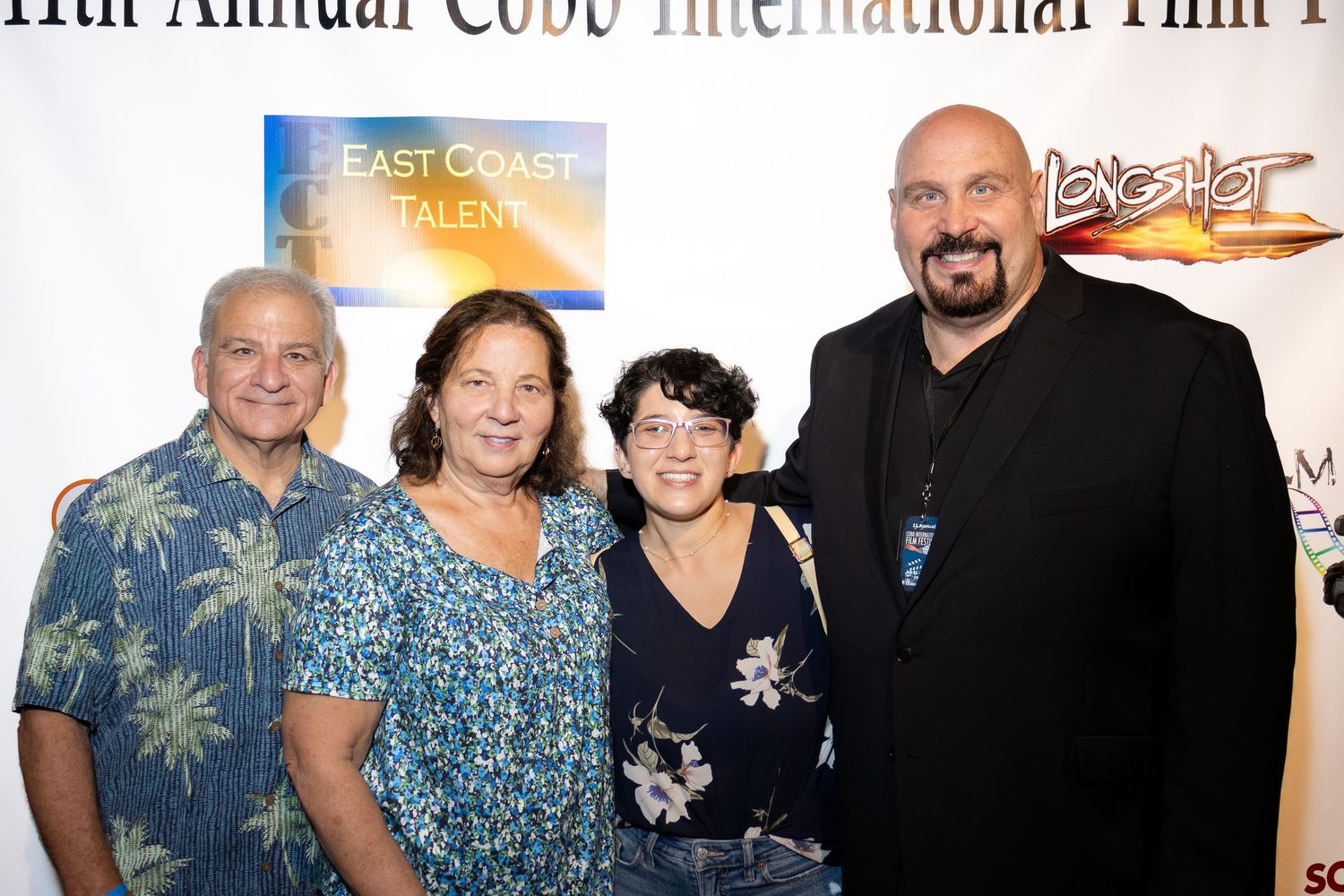 Group photo of people at a film festival event with formal attire against a dark background.