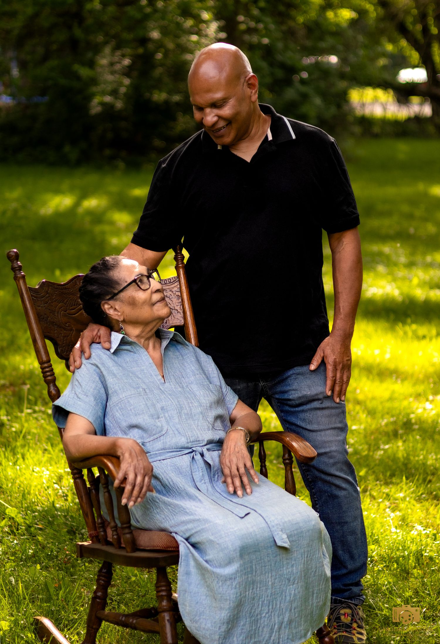 A series of candid moments captured in a sunlit garden with two people sharing joyful laughter while sitting in a wooden chair.