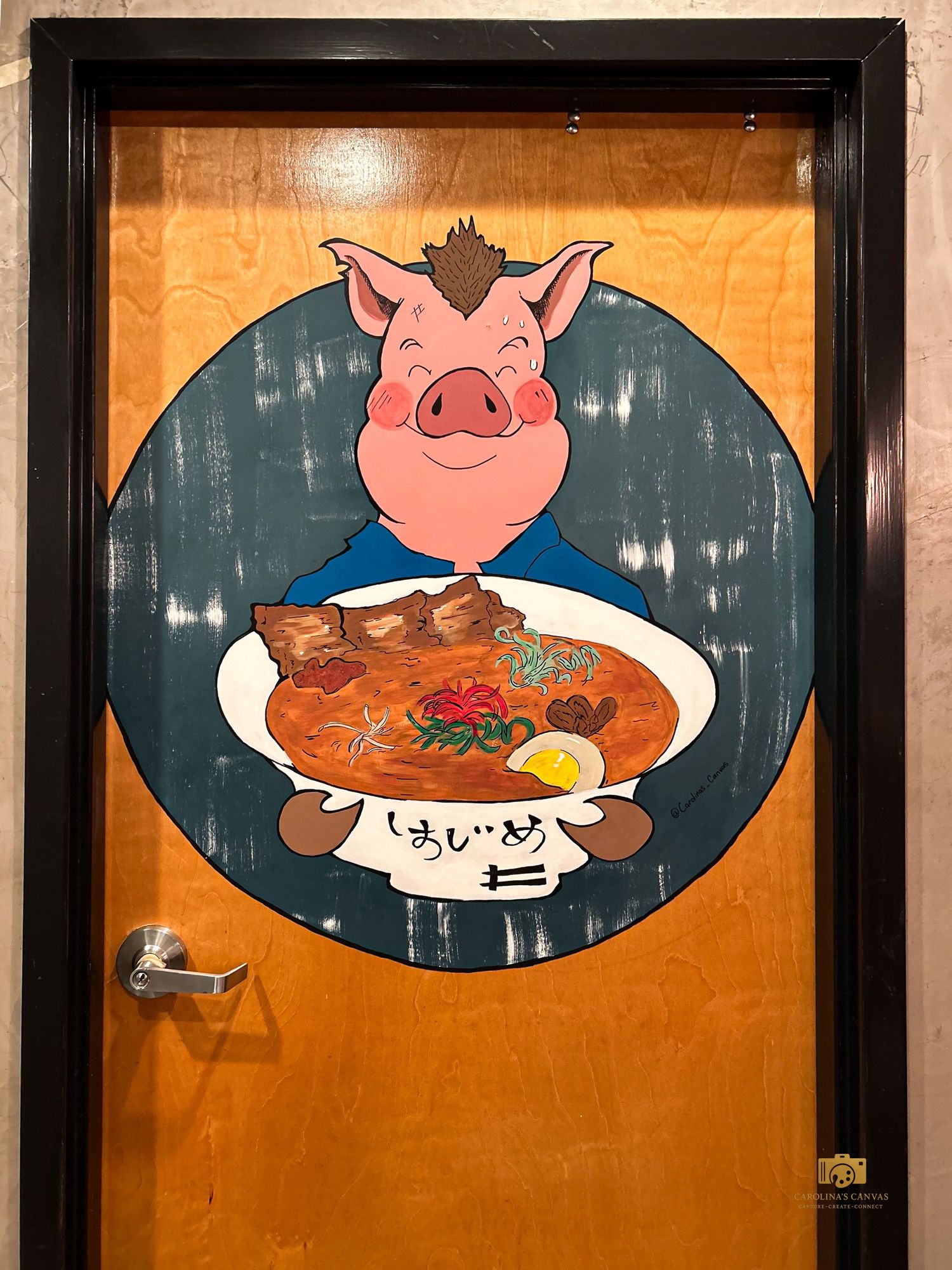 Decorative restaurant wall art featuring cartoon pig illustrations and Japanese ramen bowls on dark oval panels.