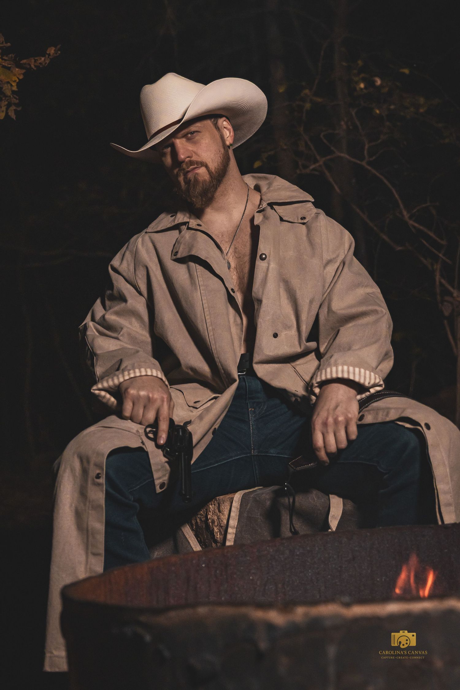 A cowboy in a light-colored jacket sits in a moody, dramatic lighting setup against a dark background.