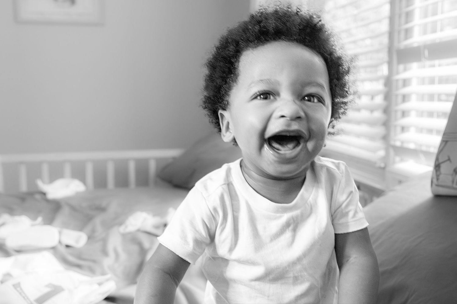 A series of black and white photos showing a baby laughing and making various joyful expressions.
