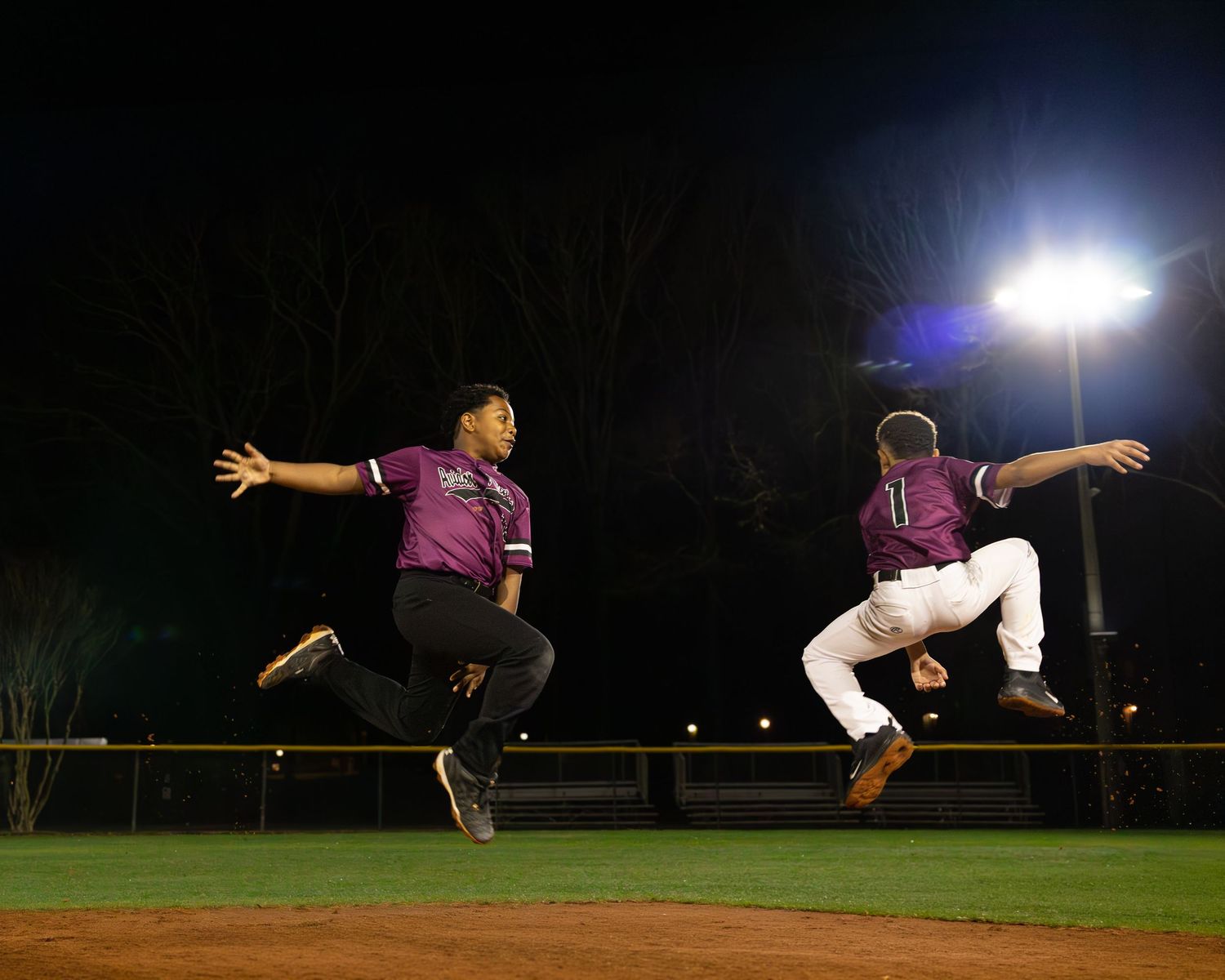 Baseball player demonstrating sliding techniques on a field at night.