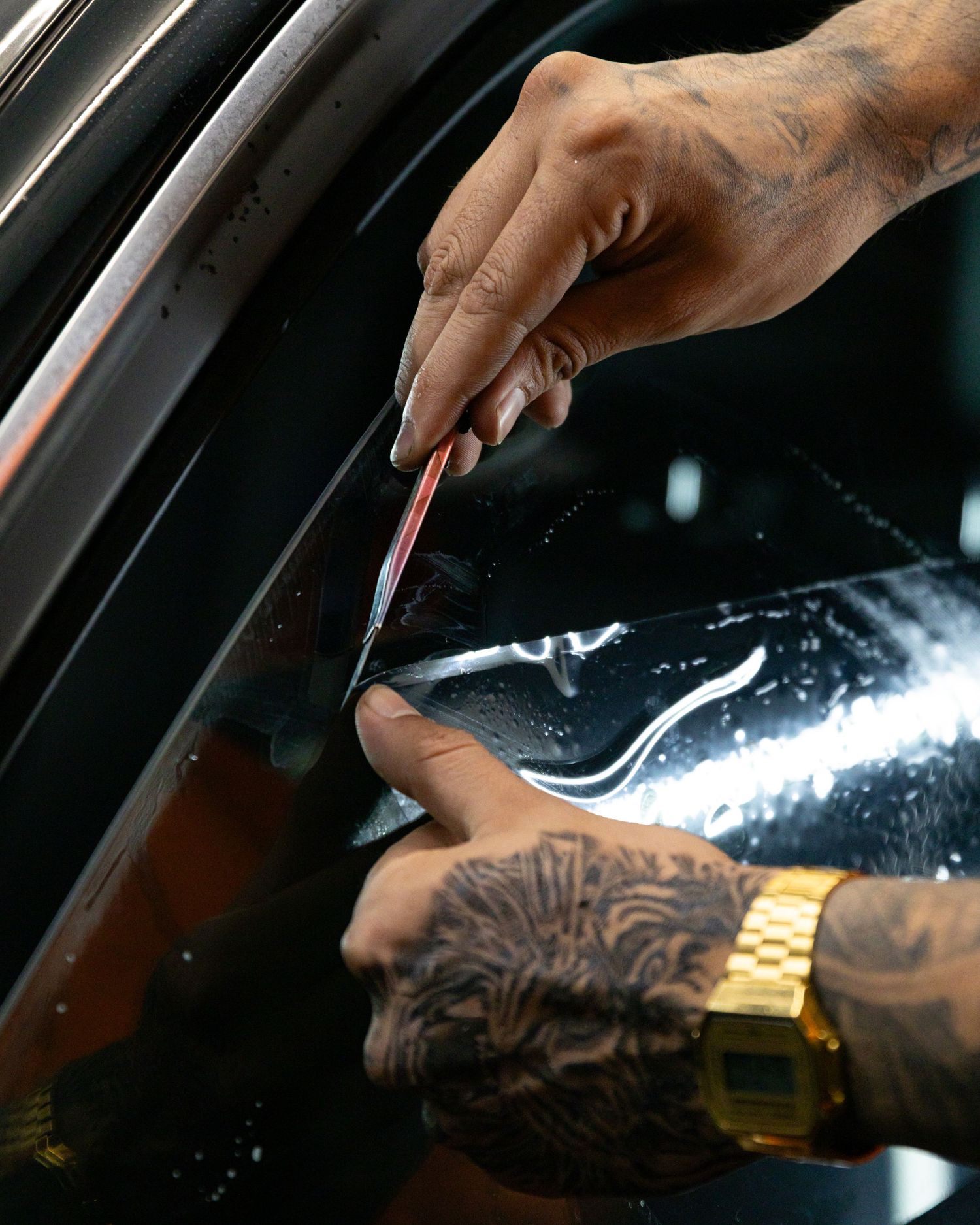 Tattooed hands with a gold watch prepare lines of white powder on a dark surface. marketing and business photography