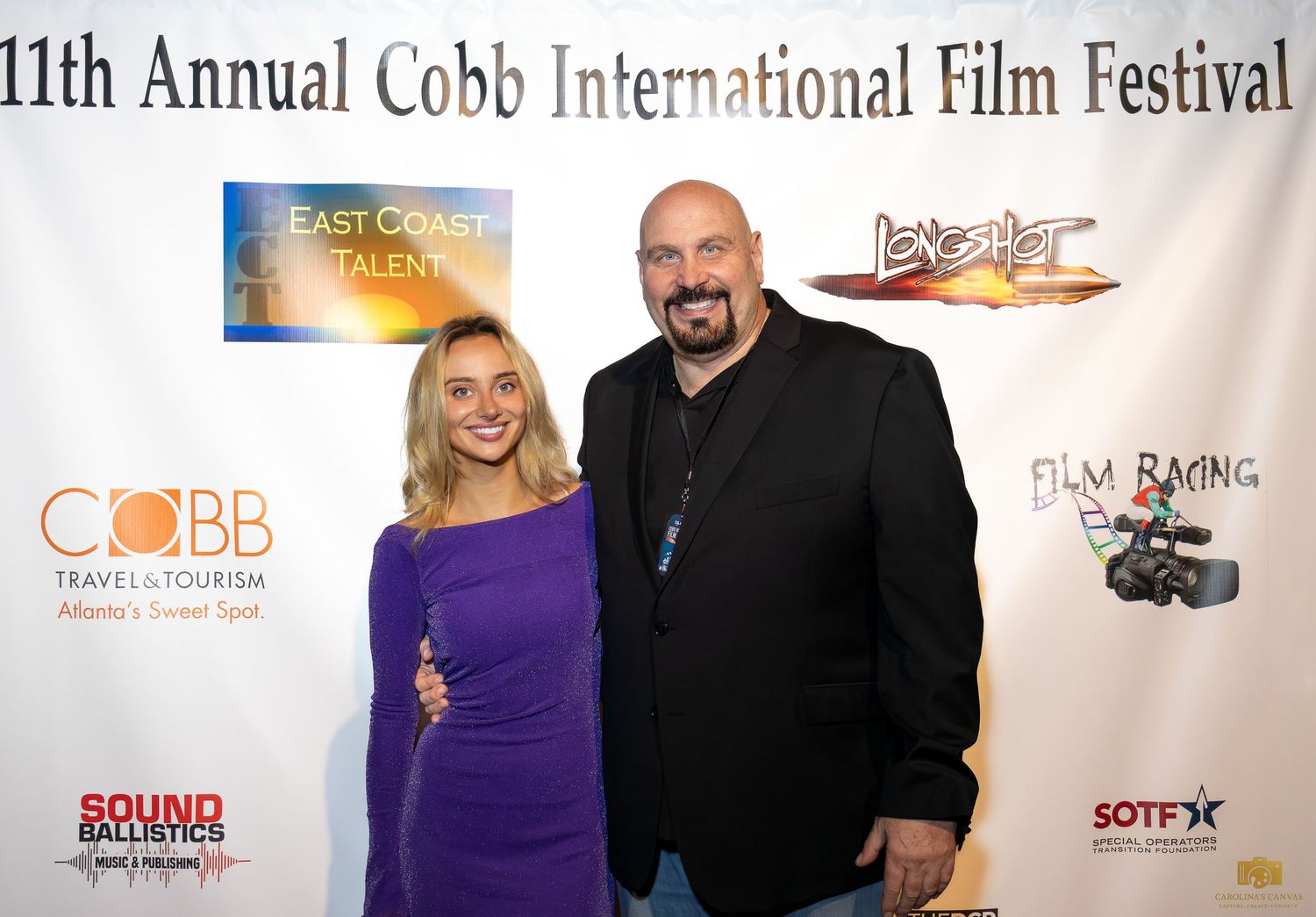 People gather for photos at the Cobb International Film Festival with event banners and sponsor logos visible.